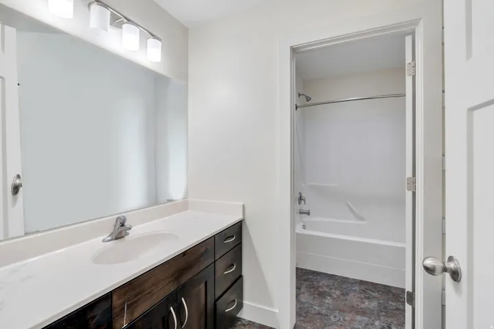 Bathroom with vanity, stone finish floors, and shower / washtub combination