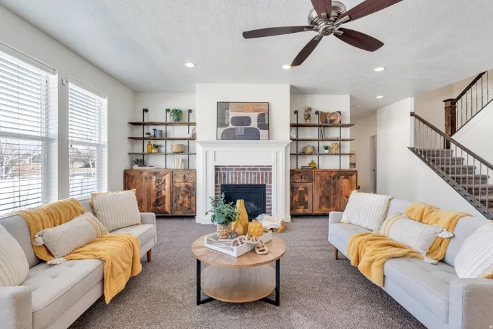 Living room with a brick fireplace, recessed lighting, carpet flooring, a textured ceiling, and ceiling fan