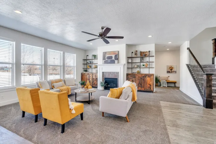 Living area featuring carpet floors, recessed lighting, a fireplace, a ceiling fan, and a textured ceiling