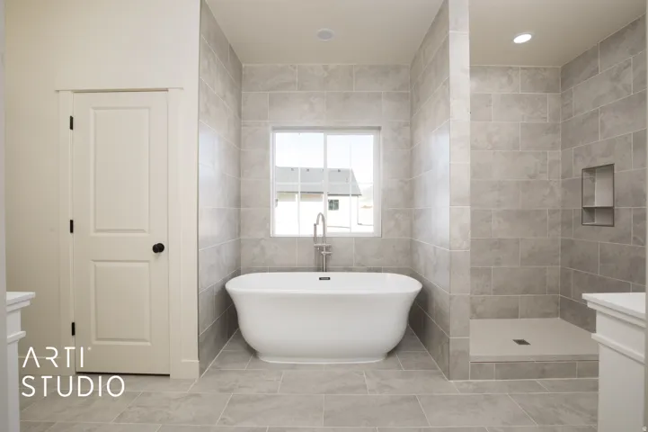 Full bathroom with tile walls, a freestanding bath, a tile shower, vanity, and recessed lighting