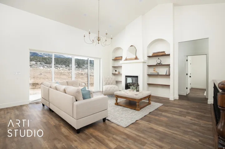 Living room with built in shelves, hanging lights, a fireplace, dark wood-style flooring, and vaulted ceiling