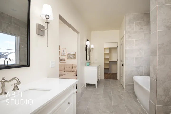 Full bathroom with two vanities, a soaking tub, tile walls, a spacious closet, and light tile patterned flooring