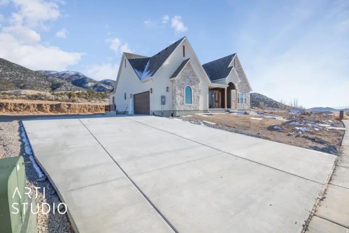 View of front facade with a mountain view, stone siding, concrete driveway, stucco siding, and a garage