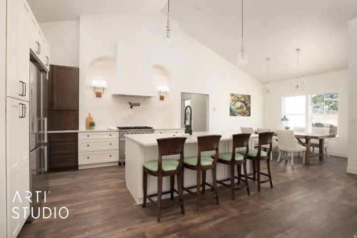 Kitchen featuring a kitchen bar, a center island with sink, lofted ceiling, backsplash, and dark wood-style flooring