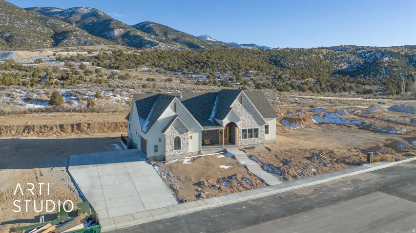 View of front facade featuring a mountain view, stone siding, a porch, and concrete driveway