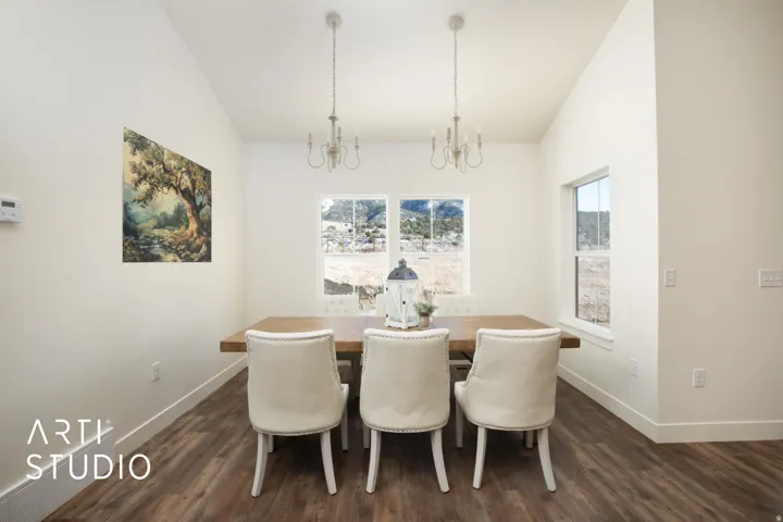 Dining space with vaulted ceiling, dark wood-type flooring, and suspended lighting