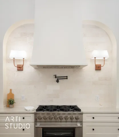 Kitchen with high end stainless steel range oven, light stone countertops, water heater, white cabinetry, and backsplash