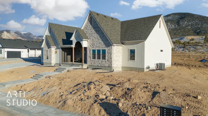 View of front of home with a mountain view, stone siding, roof with shingles, and stucco siding
