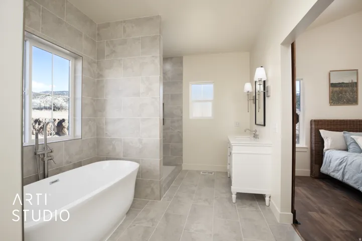 Bathroom featuring connected bathroom, tile walls, a freestanding bath, vanity, and tile patterned flooring