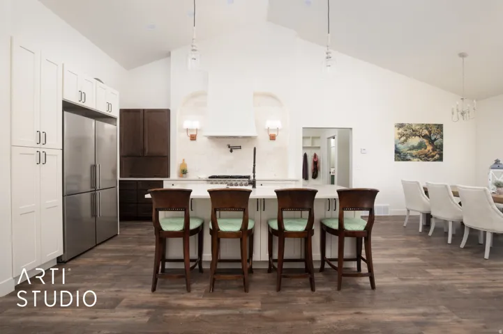 Kitchen with a kitchen island with sink, dark wood finished floors, high end fridge, a breakfast bar, and lofted ceiling