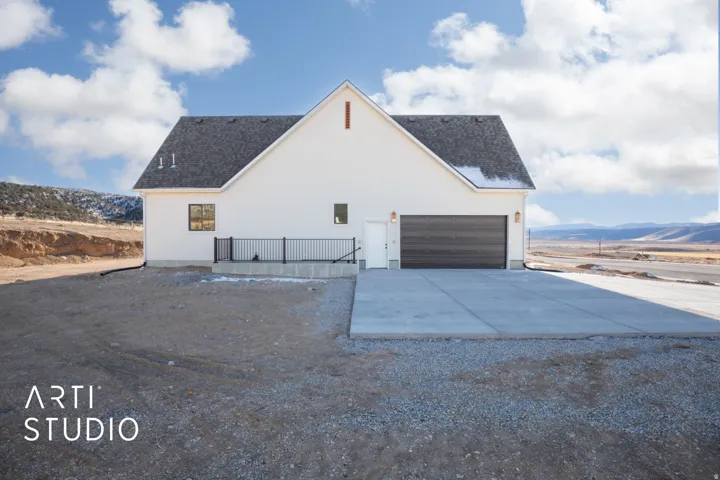 View of side of home with driveway, a mountain view, stucco siding, and a garage
