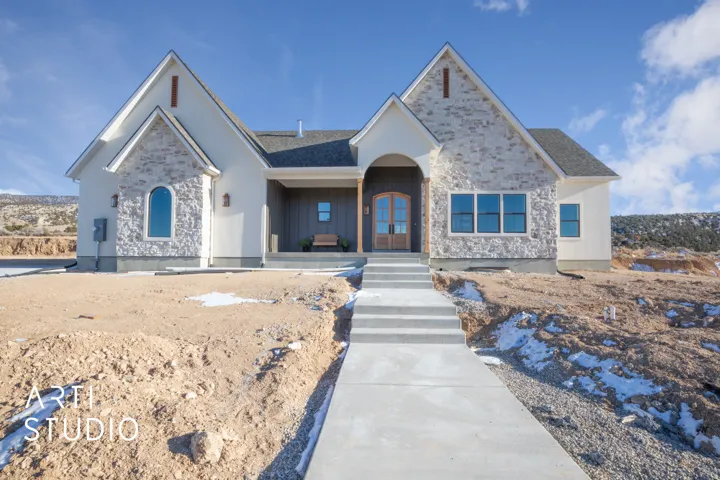 View of front of house with stone siding, covered porch, and roof with shingles
