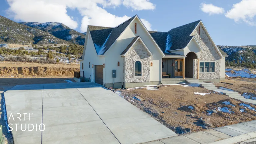 View of front facade featuring stone siding, a mountain view, concrete driveway, and an attached garage