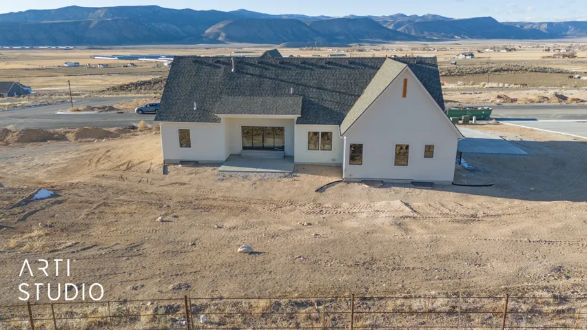 View of front of property with a mountain view, a patio area, stucco siding, roof with shingles, and a desert view