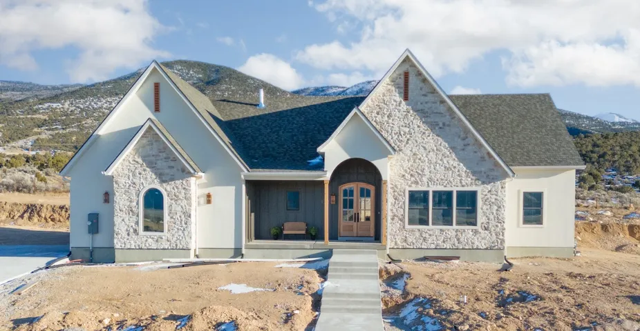 View of front facade featuring stone siding, a porch, a mountain view, and roof with shingles