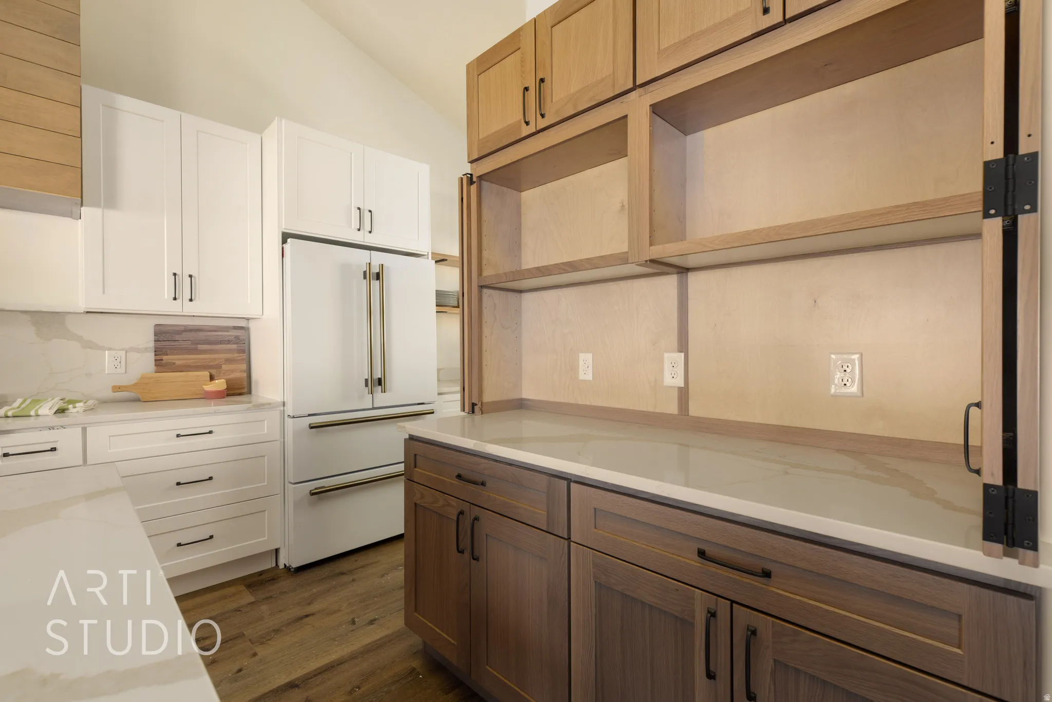 Kitchen featuring dual tone cabinets, open shelves, high end white fridge, dark wood-type flooring, and light stone counters