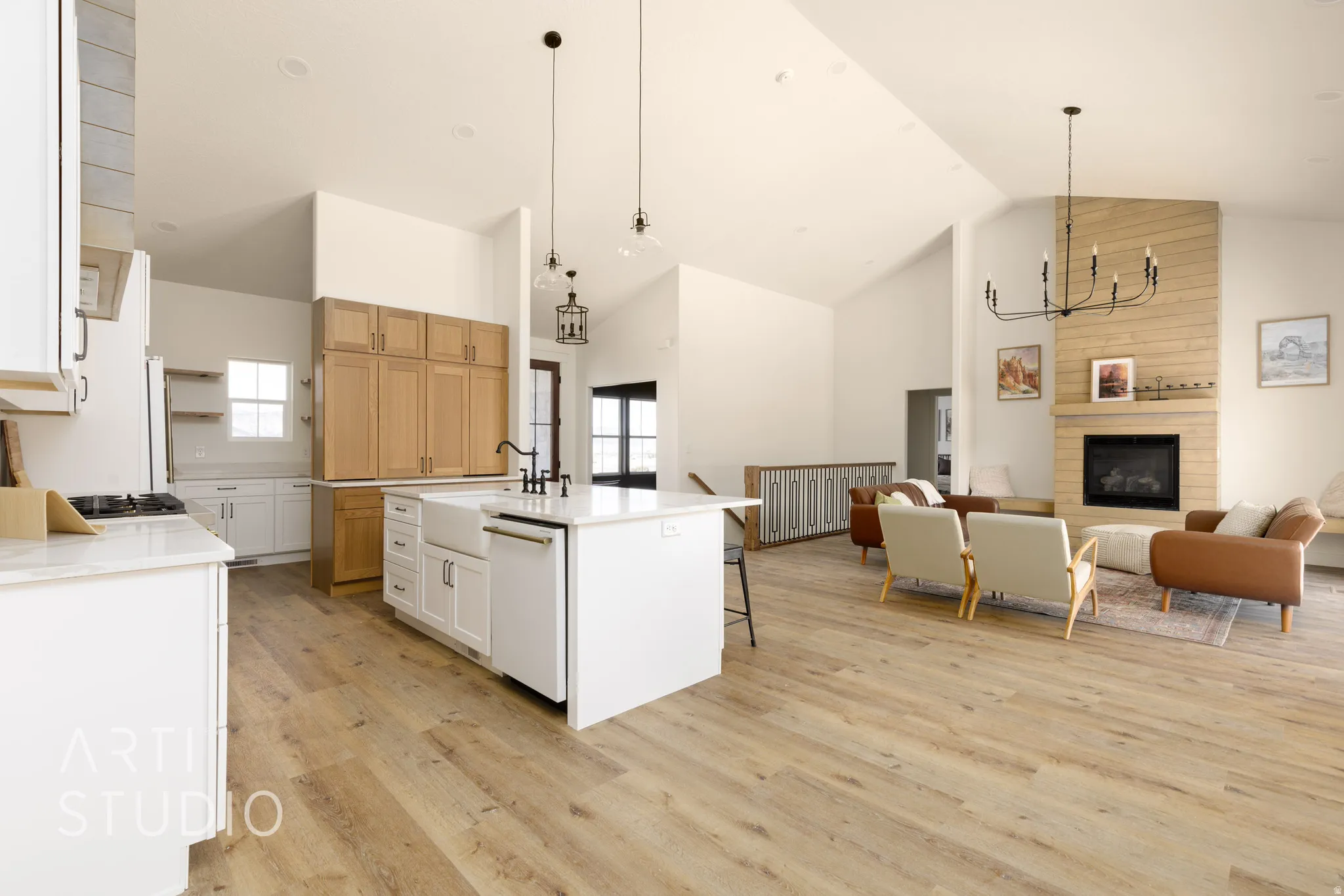 Dual tone kitchen featuring a high ceiling, open floor plan, light wood finished floors, a kitchen breakfast bar, and a kitchen island with sink