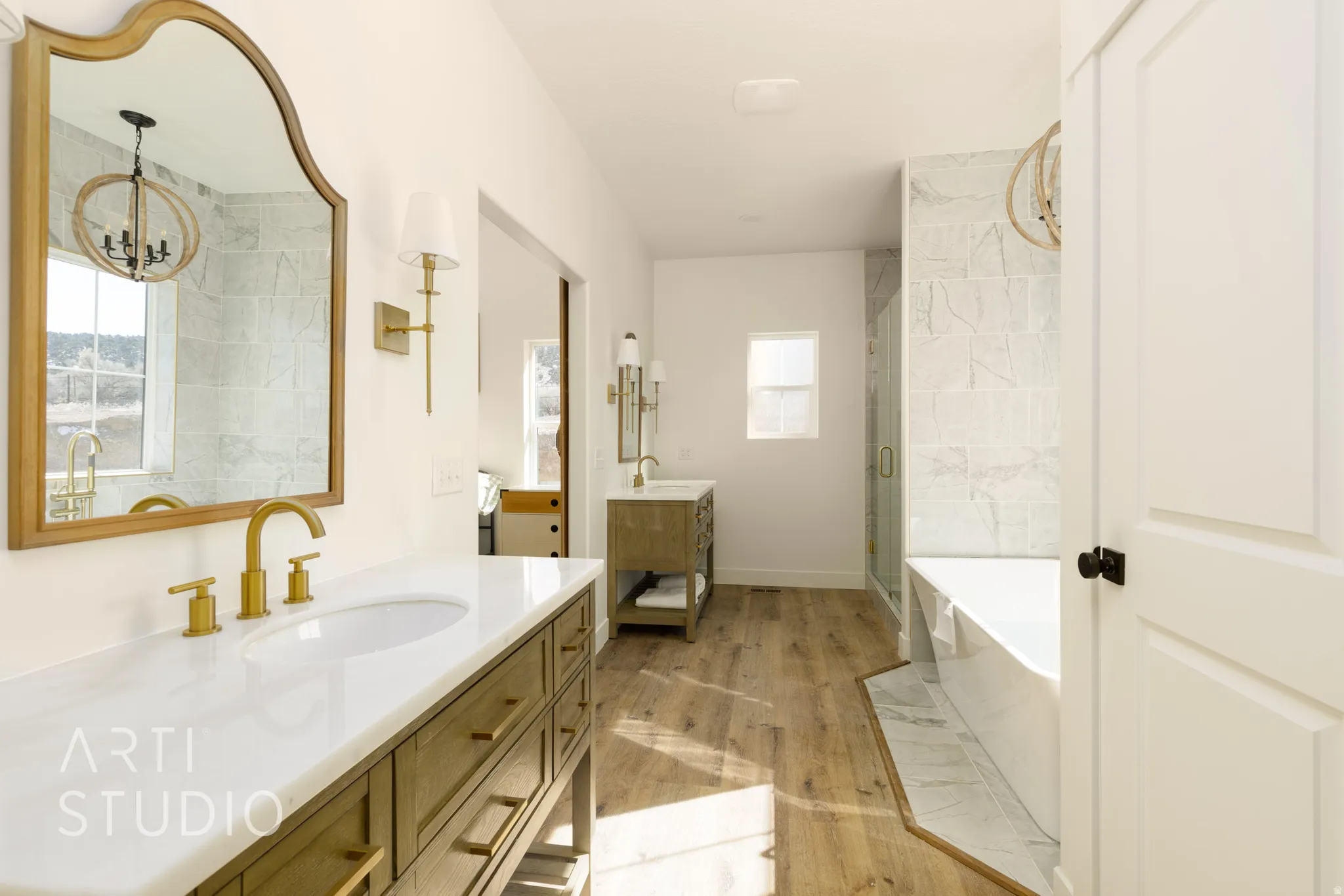 Full bathroom featuring a freestanding tub, two vanities, a shower stall, and light wood finished floors