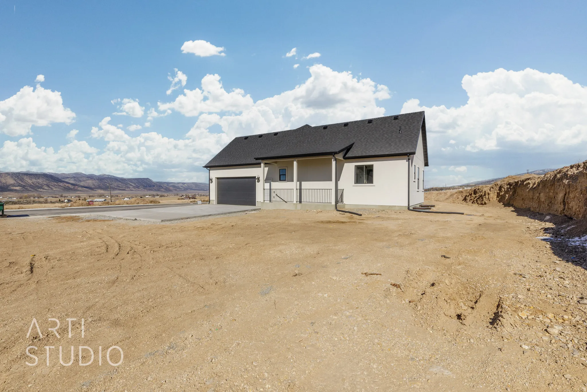 Back of property with a mountain view, driveway, an attached garage, roof with shingles, and stucco siding