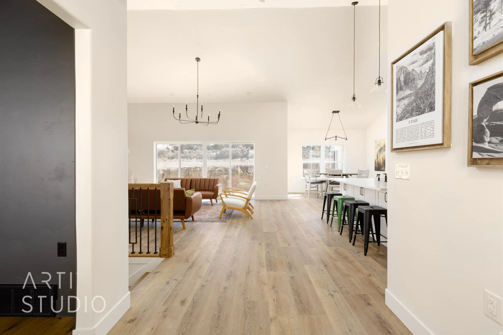 Corridor with light wood-type flooring, suspended lighting, and a high ceiling