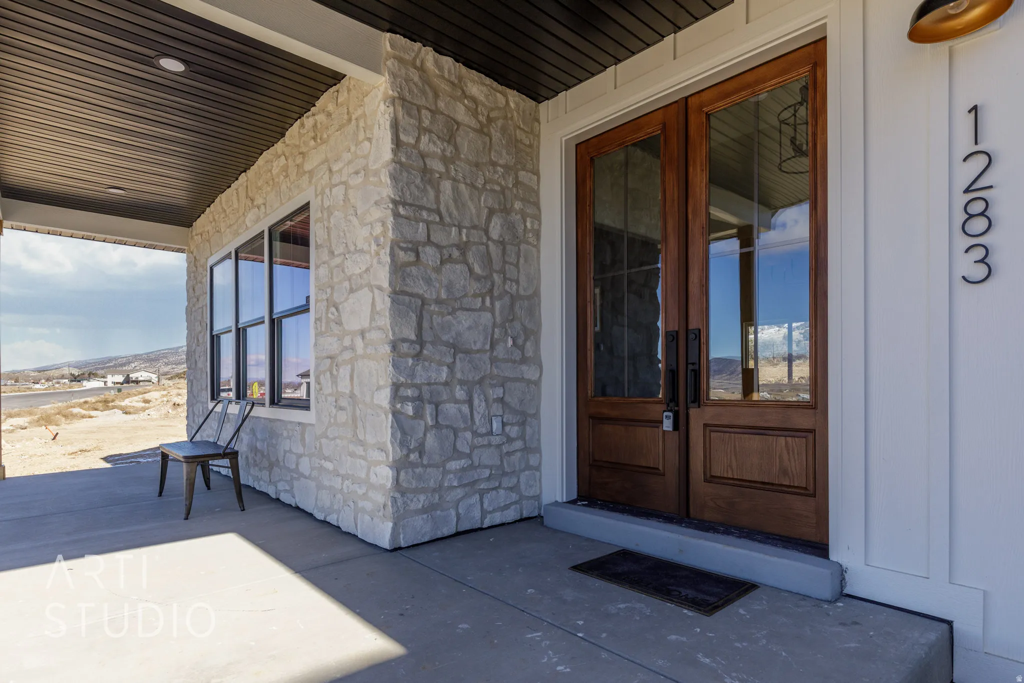 View of exterior entry featuring stone siding, french doors, and covered porch