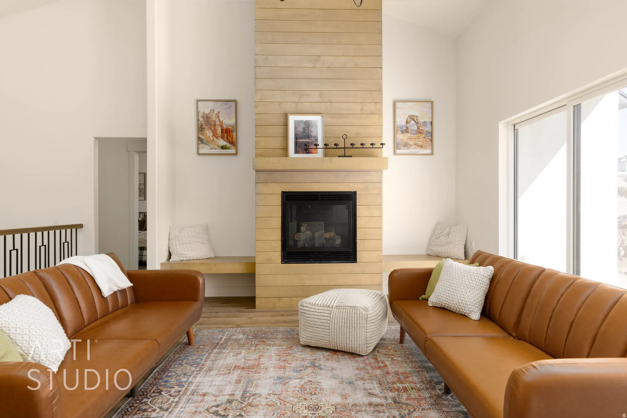 Living room with vaulted ceiling, wood finished floors, a glass covered fireplace, and plenty of natural light