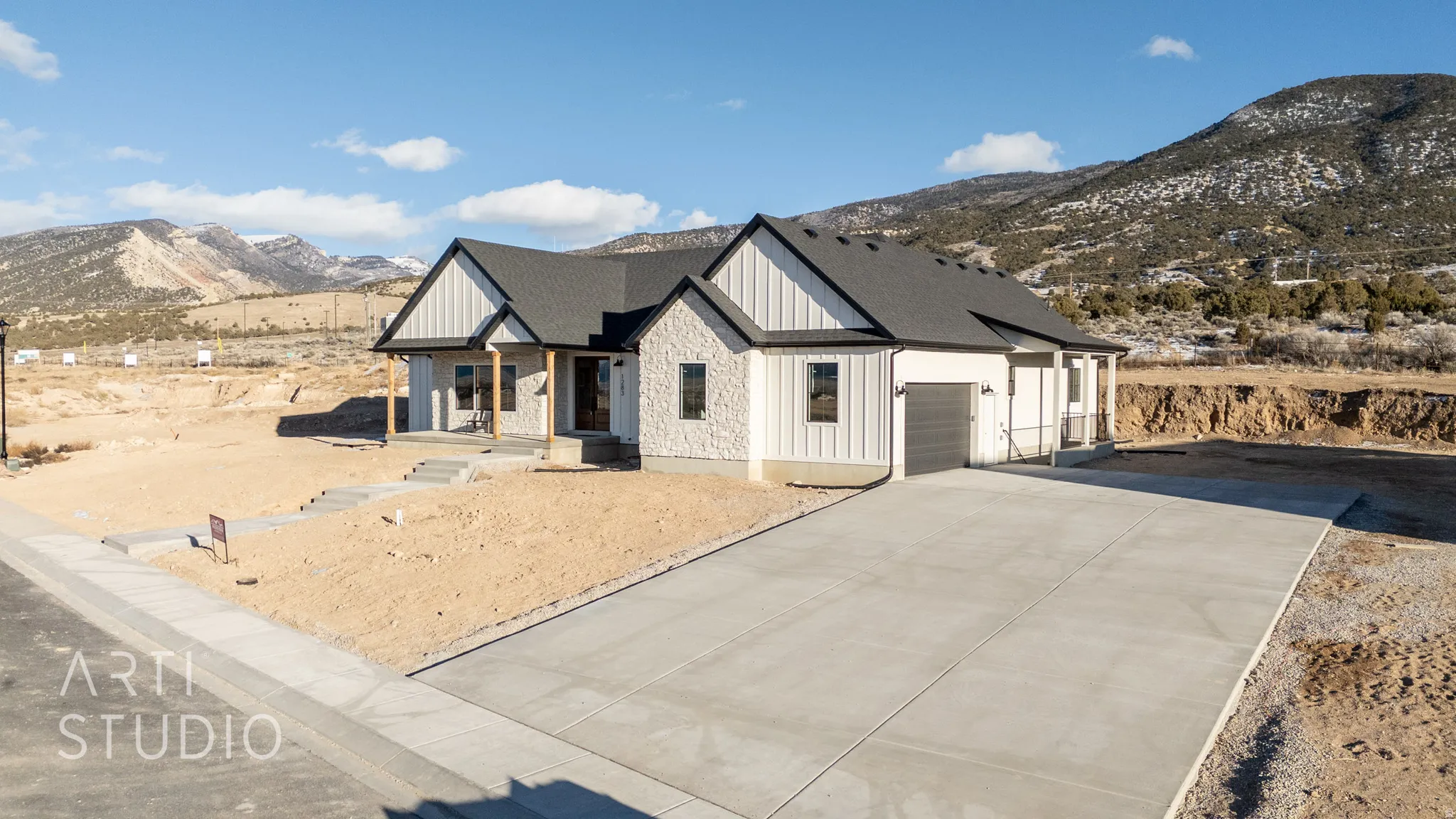 Modern inspired farmhouse with a mountain view, covered porch, board and batten siding, a garage, and concrete driveway