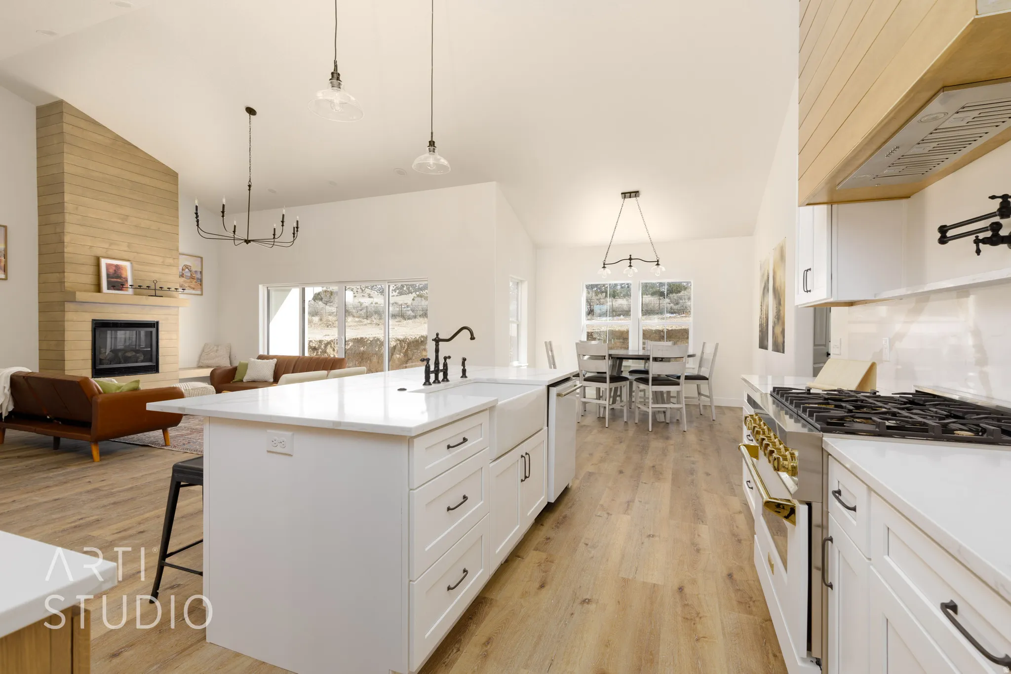 Kitchen with range with gas stovetop, lofted ceiling, open floor plan, light wood-type flooring, and white cabinets