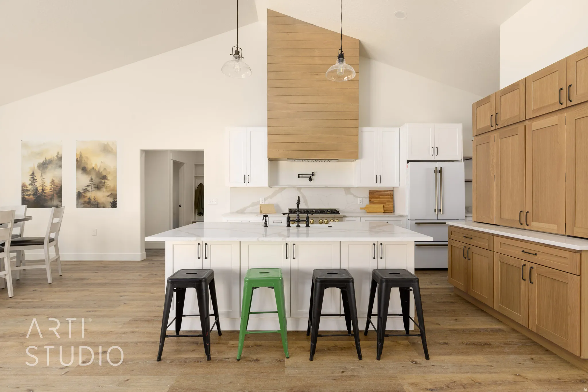 Dual tone kitchen featuring pendant lighting, two tone cabinetry, a kitchen island with sink, high end white fridge, and light wood-type flooring