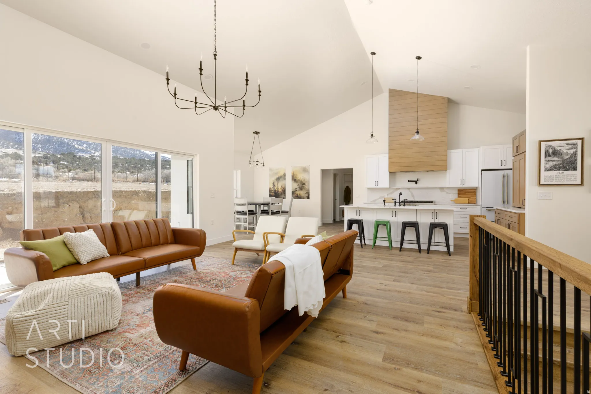 Living area with light wood-style floors, hanging lights, and vaulted ceiling