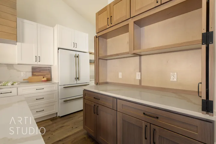 Kitchen featuring dual tone cabinets, open shelves, high end white fridge, dark wood-type flooring, and light stone counters