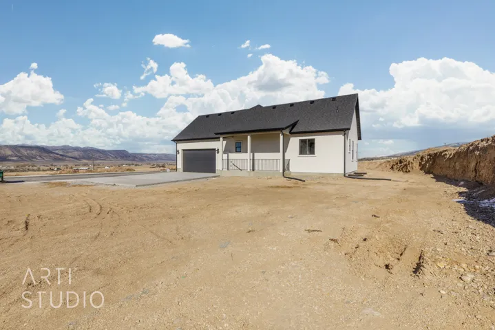 Back of property with a mountain view, driveway, an attached garage, roof with shingles, and stucco siding