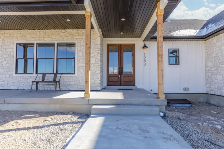 Property entrance featuring stone siding, a porch, french doors, and board and batten siding
