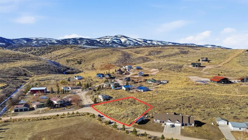 Aerial view of sparsely populated area featuring property parcel outlined and nearby suburban area