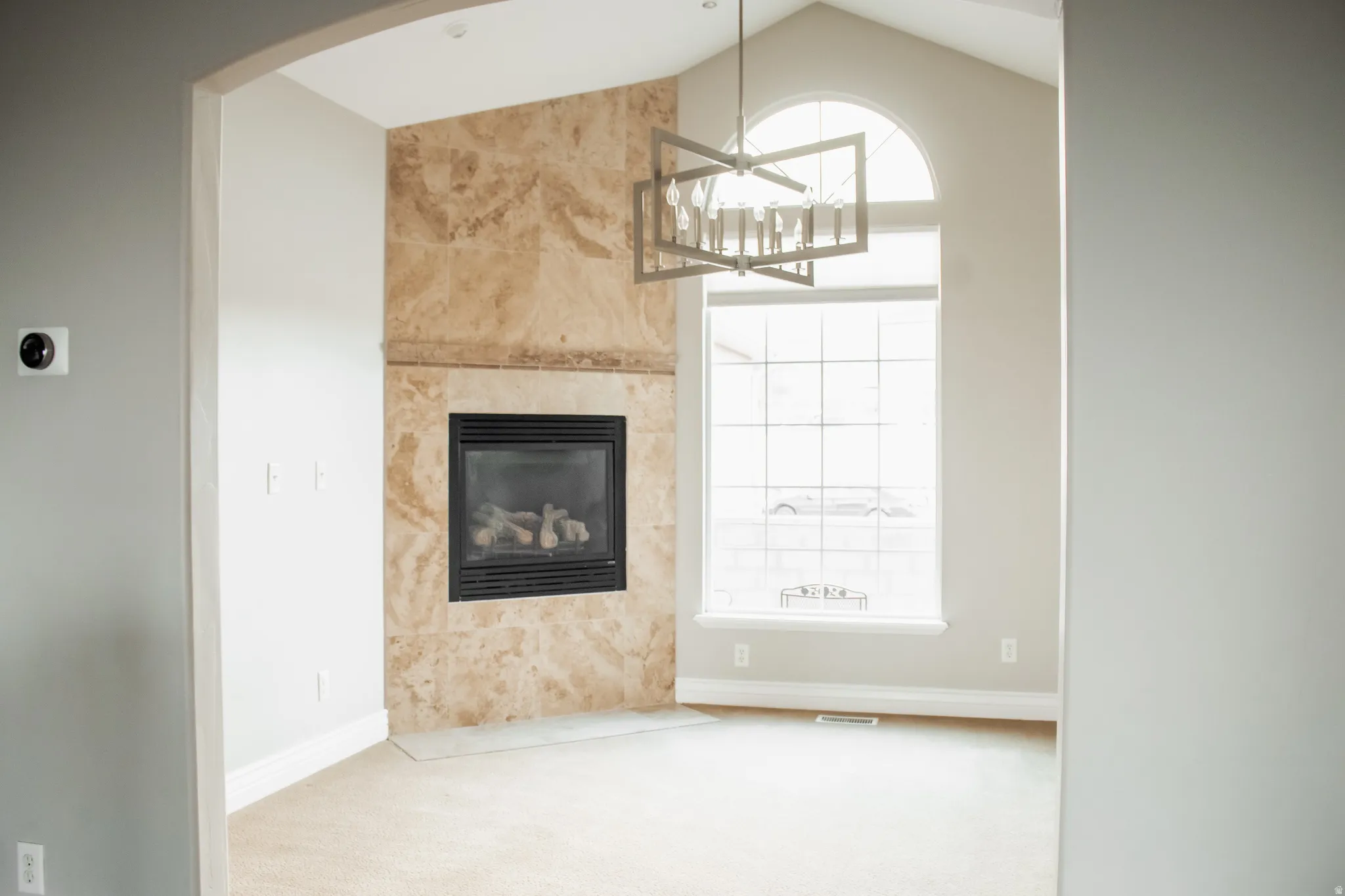 Open dining area featuring arched walkways, hanging light fixture and a fireplace.