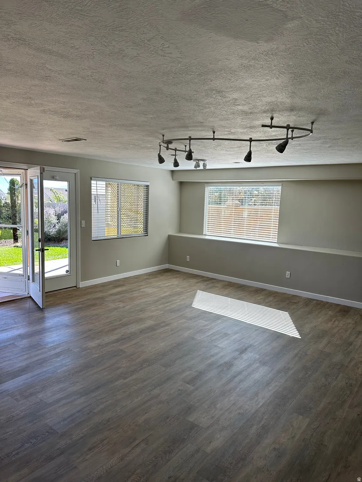 Unfurnished dining area featuring wood finished floors and rail lighting.