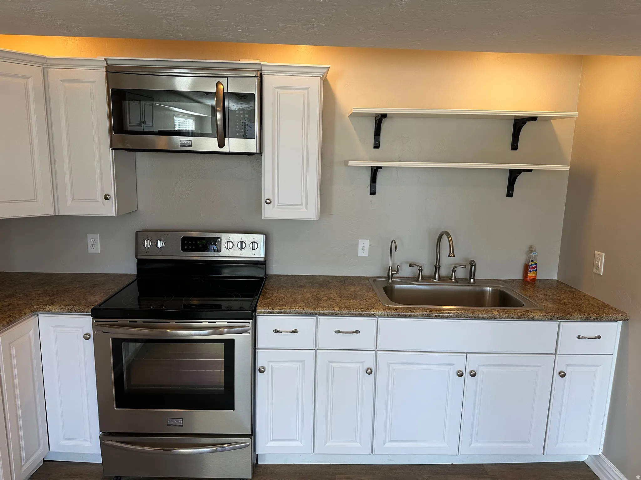Kitchen with white cabinetry, stainless steel appliances, open shelves, and dark stone countertops