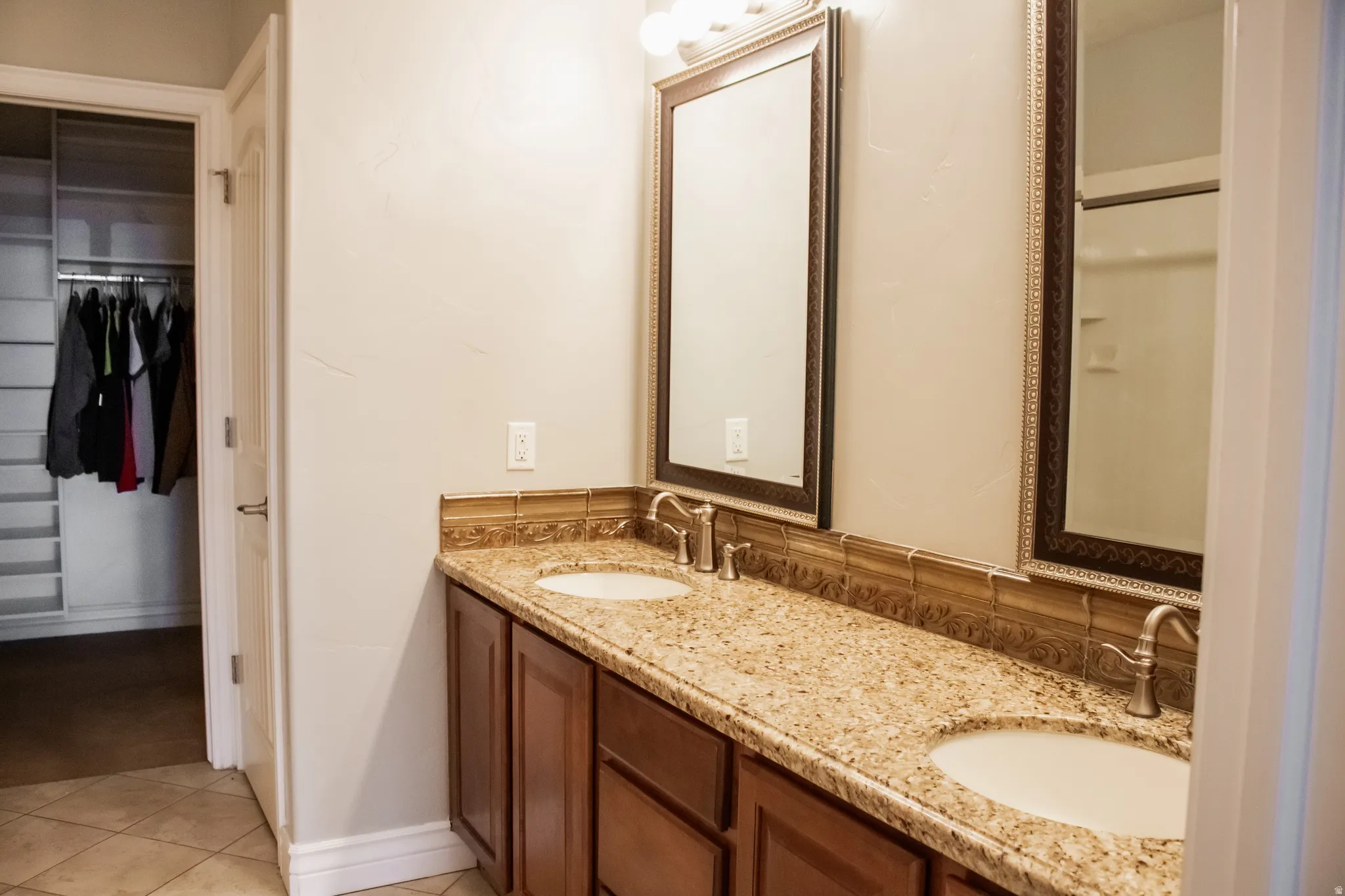 Master Bathroom with double vanity, a spacious closet, and light tile patterned floors