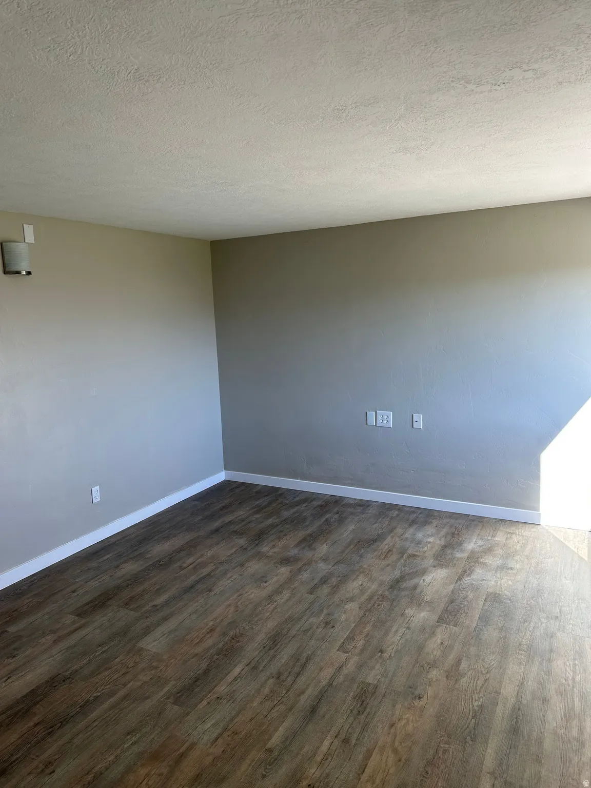 Spare room with a textured ceiling and dark wood-style flooring