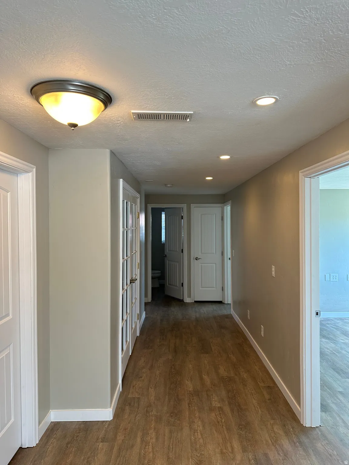 Hall with wood-style floors, a textured ceiling, and recessed lighting