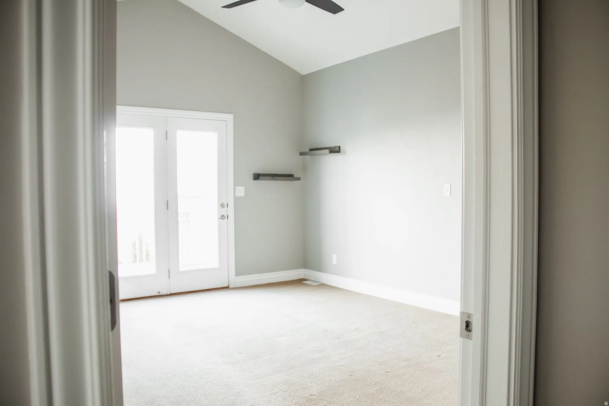 Master bedroom featuring vaulted ceiling, light carpet, and a ceiling fan