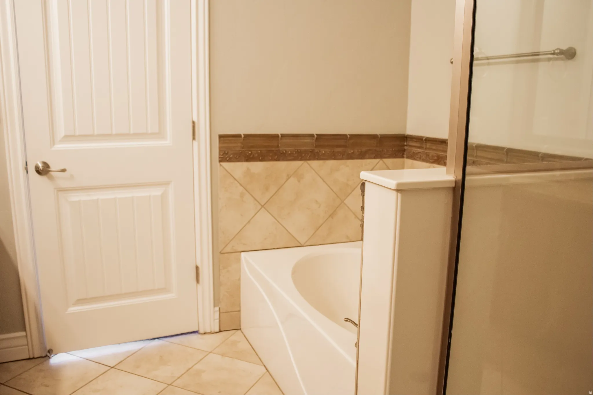 Full master bathroom featuring a garden tub, tile patterned floors, tile walls, and a wainscoted wall