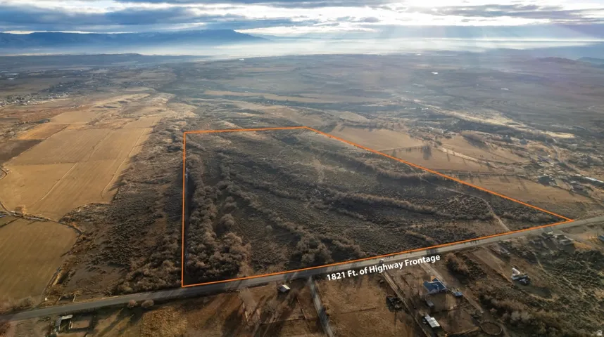 Overview of rural landscape with property parcel outlined and a mountain backdrop