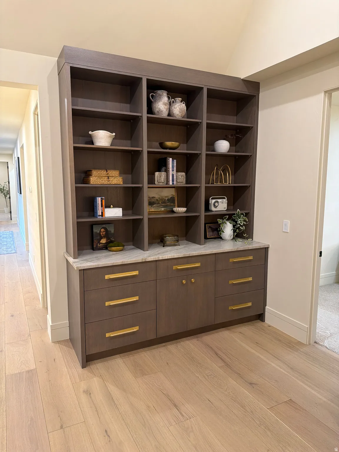 Bar area with modern cabinets, light wood-style flooring, light stone countertops, lofted ceiling, and dark wood finish cabinets