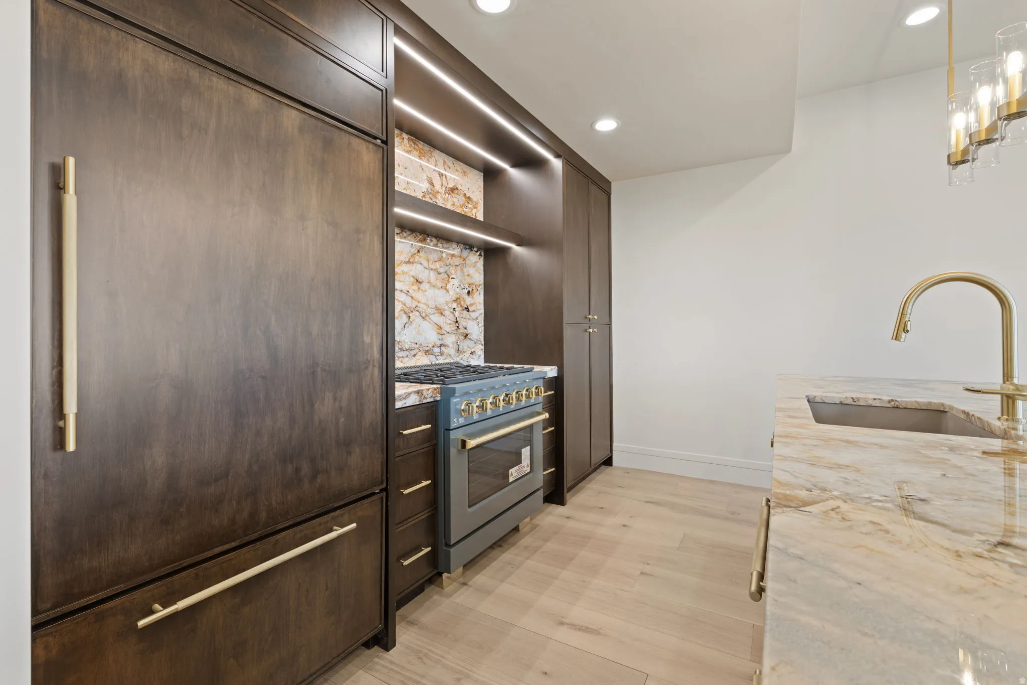 Second Kitchen with light stone countertops, high end gas range, light wood-style floors, pendant lighting, and open shelves