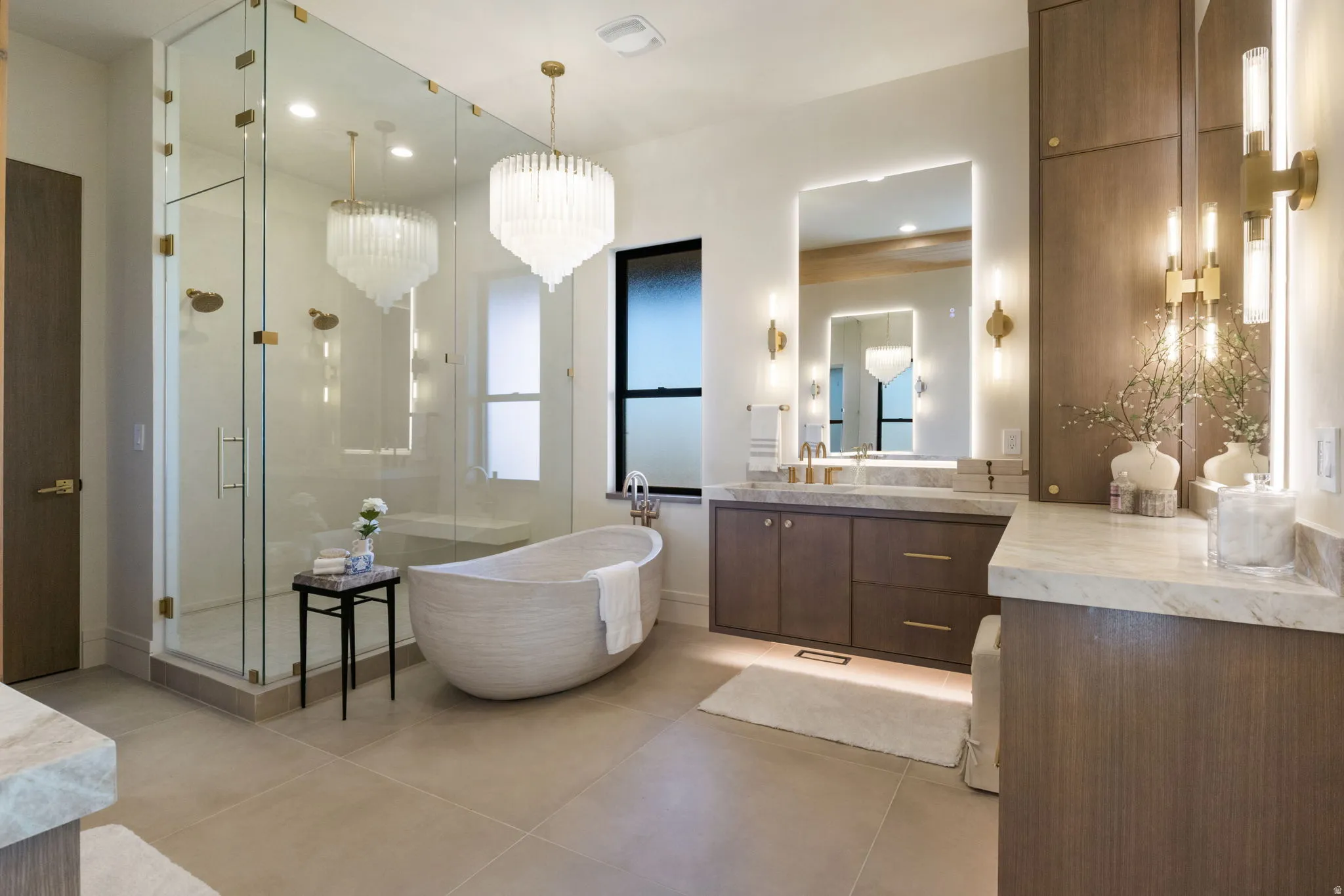 Bathroom with vanity, a freestanding tub, a stall shower, and suspended lighting