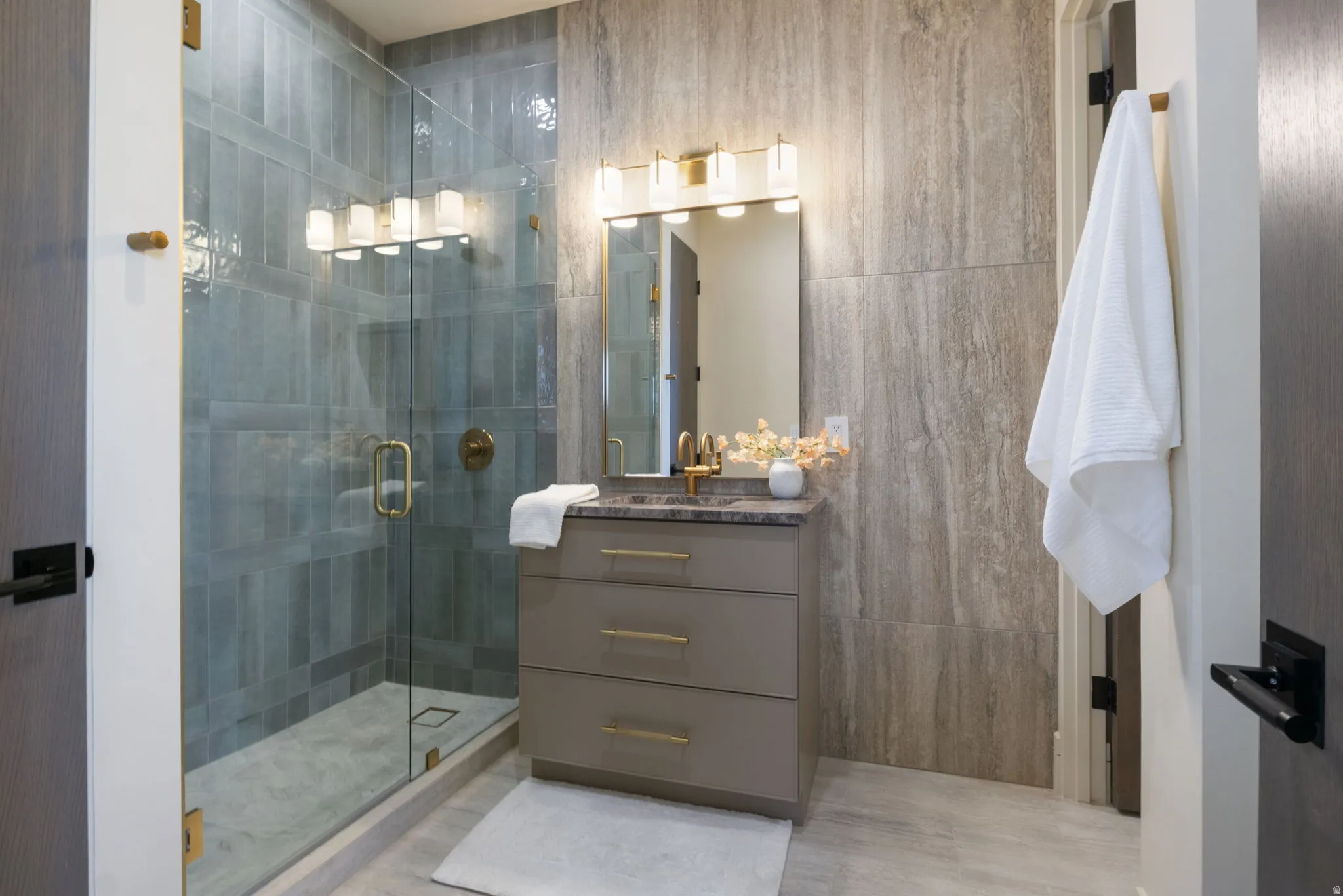 Bathroom with vanity, a stall shower, and tile walls