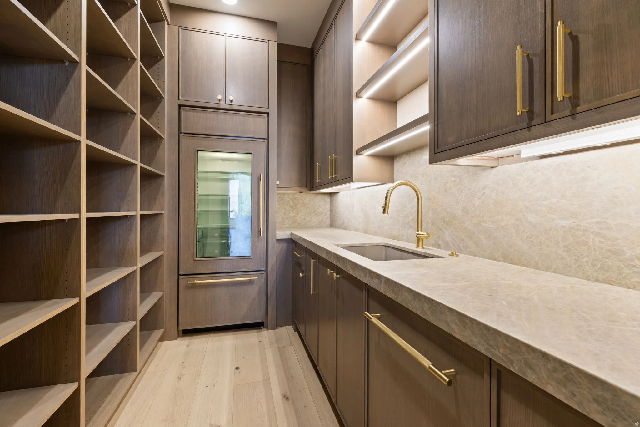 Butler's Pantry with floor to ceiling shelving, a Sub Zero Beverage refrigerator and freezer, pebble ice maker, dish washer and sink. With white oak cabinetry, Mojave quartzite countertops and full height backsplash.