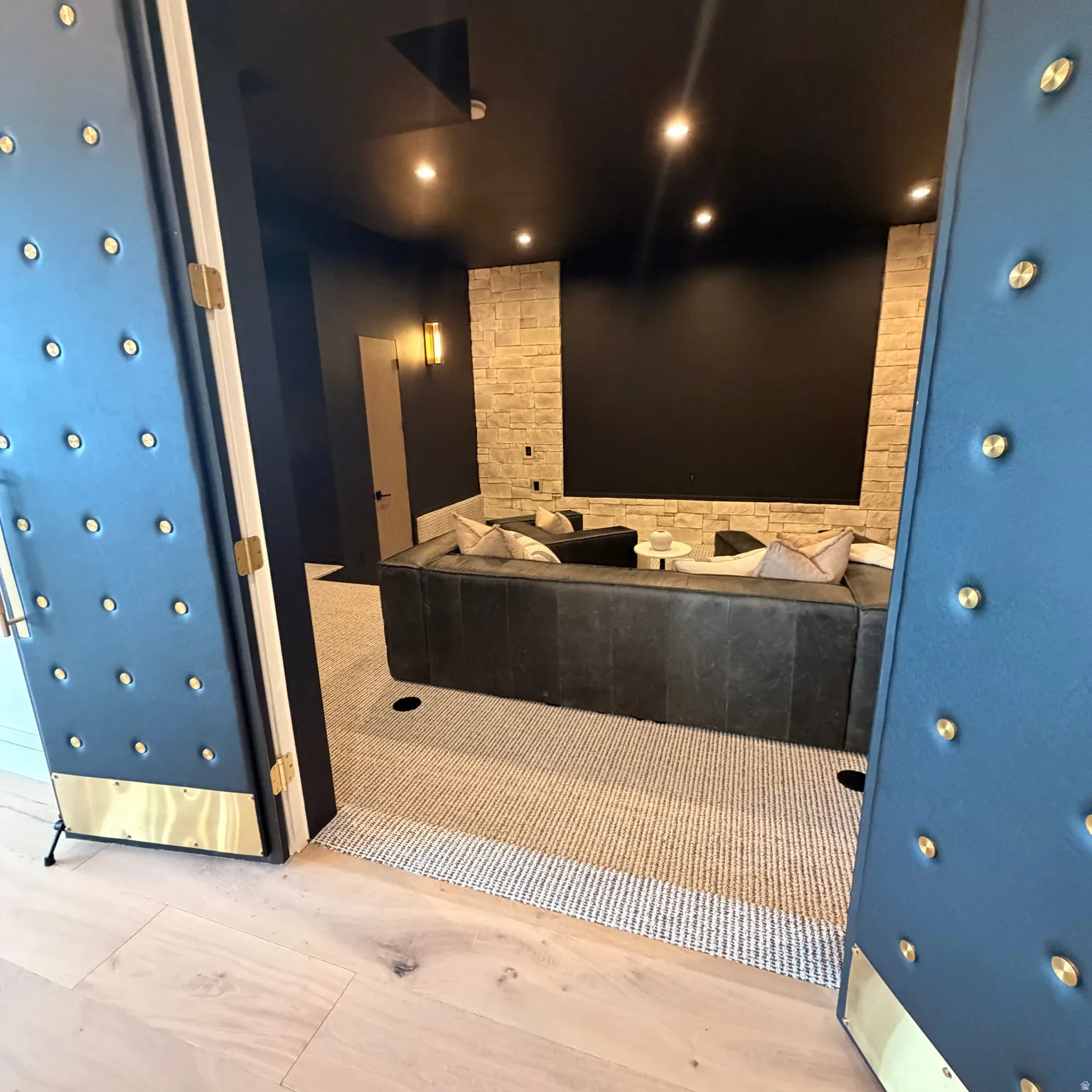 Movie room with stone, leather doors with brass accents.