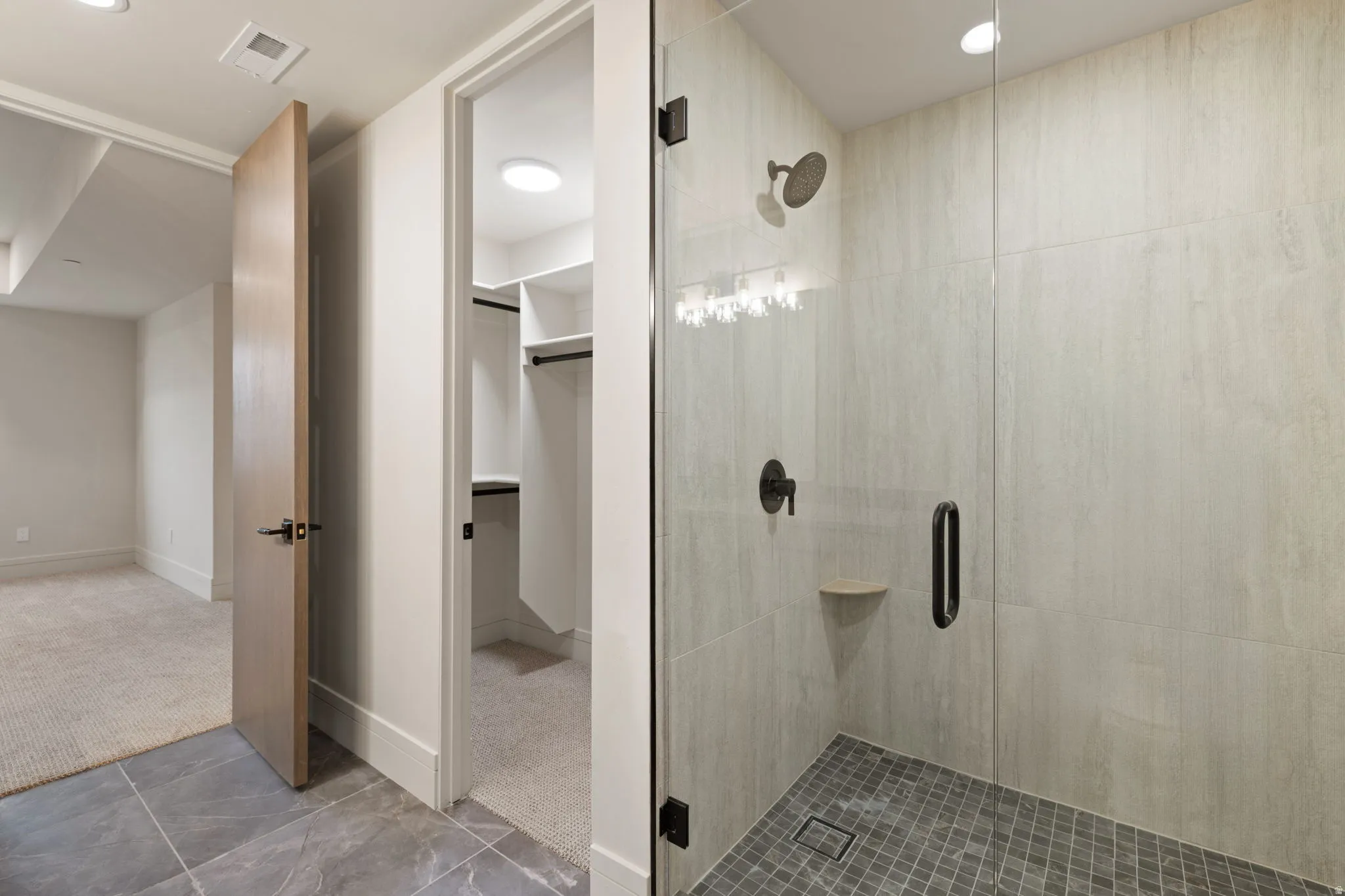 Bathroom featuring carpet flooring, a shower stall, a walk in closet, tile patterned flooring, and recessed lighting